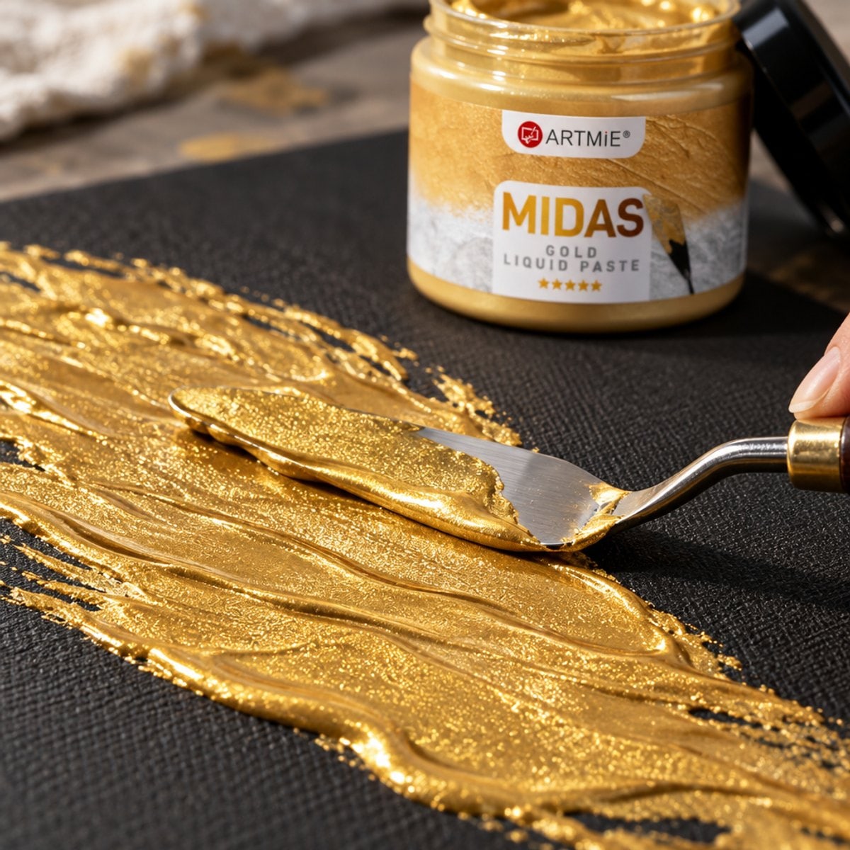 Nanašanje zlate kovinske paste ARTMIE MIDAS z lopatico na črno platno — makro